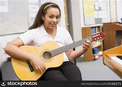 Female student learning guitar in classroom