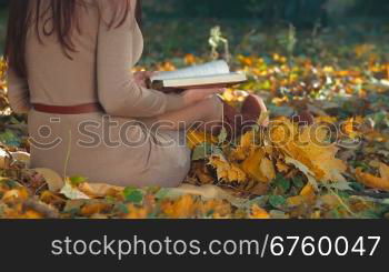 Female Student Reading Lecture Notes in Autumn Park