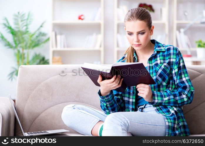 Female student reading the book sitting on the sofa