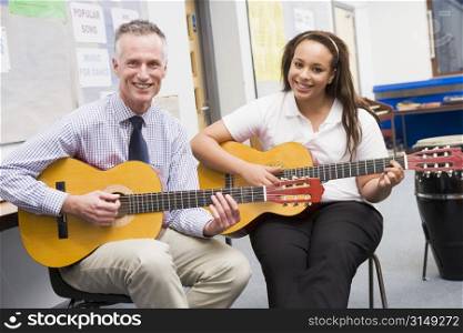 Female student receiving guitar lesson from teacher in classroom