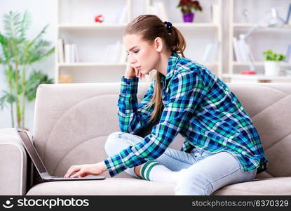 Female student sitting on the sofa with laptop