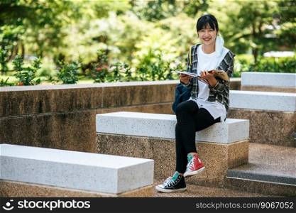 Female student sitting on the stairs and read a book.