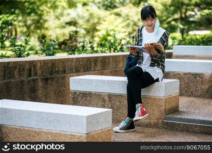 Female student sitting on the stairs and read a book.