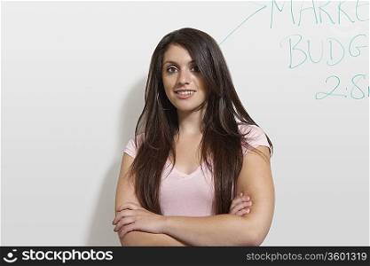 Female student standing by white board, portrait