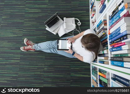 female student study in library using tablet and searching internet while Listening music and lessons on white headphones