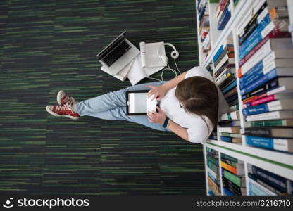 female student study in library using tablet and searching internet while Listening music and lessons on white headphones