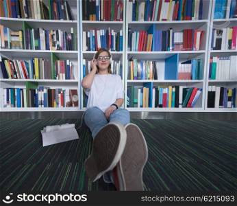 female student study in school library, using tablet and searching for information?s on internet. Listening music and lessons on white headphones