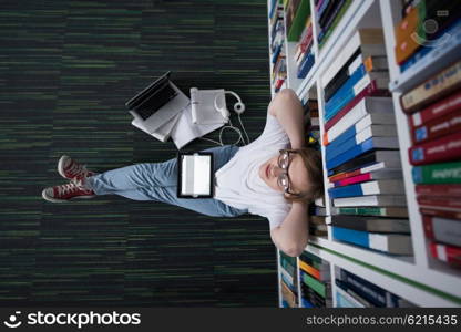 female student study in school library, using tablet and searching for information?s on internet. Listening music and lessons on white headphones