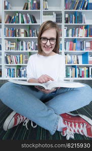 female student study in school library, using tablet and searching for information?s on internet. Listening music and lessons on white headphones