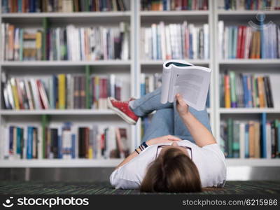 female student study in school library, using tablet and searching for information?s on internet. Listening music and lessons on white headphones