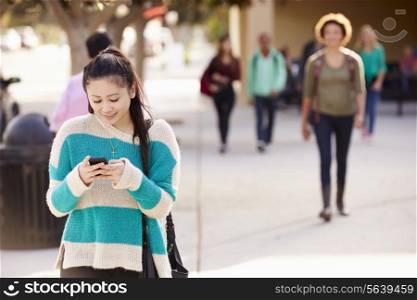 Female Student Walking To High School Using Mobile Phone