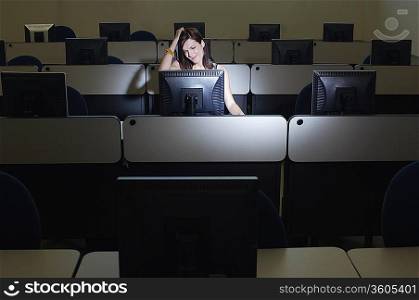 Female student with hand on head in computer classroom