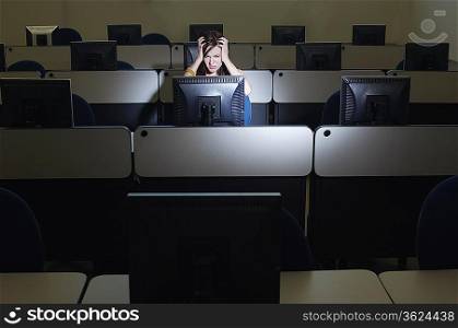 Female student with head in hands in computer classroom