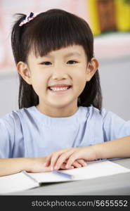 Female Student Working At Desk In Chinese School Classroom