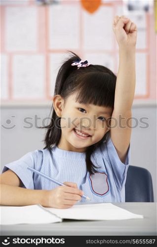 Female Student Working At Desk In Chinese School Classroom
