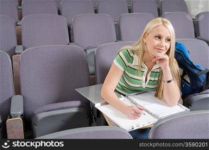 Female student writing in lecture hall