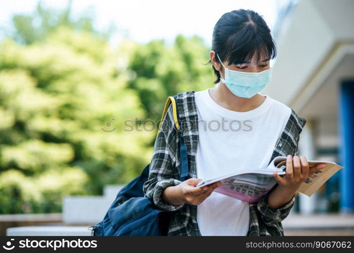 Female students wearing masks and books on the stairs.