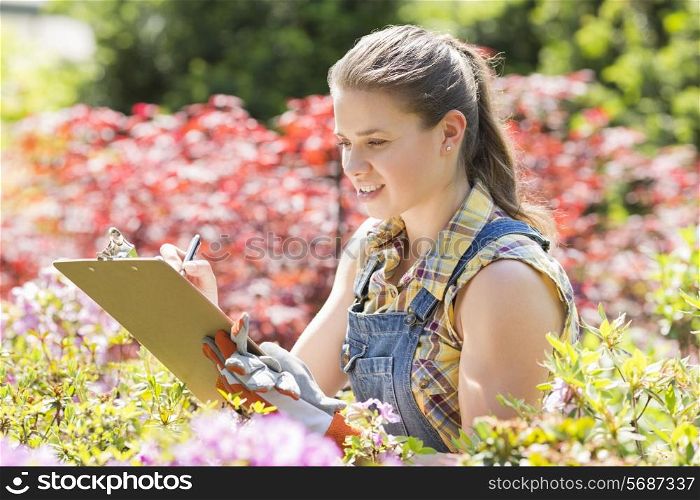 Female supervisor writing on clipboard in garden