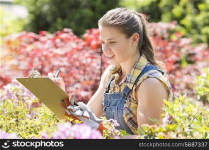 Female supervisor writing on clipboard in garden