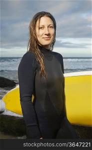 Female surfer holding surfboard on beach, portrait