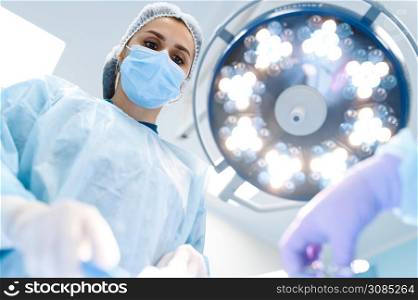 Female surgeon and assistant, professional surgery, operating room. Doctor in uniform performs operation, medical clinic worker, surgical medicine and health, healthcare in hospital. Female surgeon and assistant, professional surgery