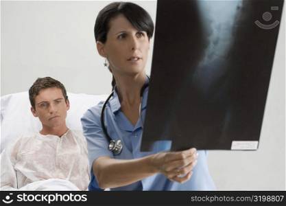Female surgeon examining an X-Ray report with a patient in the background