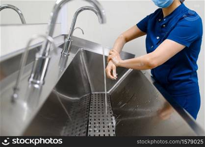 Female surgeon in mask washes hands, preparing for surgery operation. Doctor in uniform, medical clinic worker, medicine and health, healthcare in hospital. Female surgeon washes hands, preparing for surgery