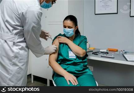 Female surgeon receiving coronavirus vaccine at doctor’s office