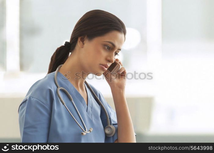 Female surgeon using cell phone in hospital