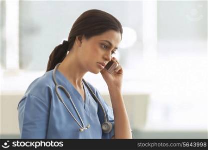 Female surgeon using cell phone in hospital