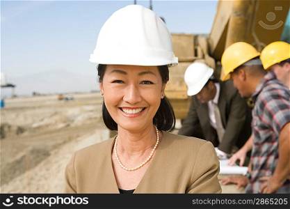 Female surveyor and construction workers on site, portrait