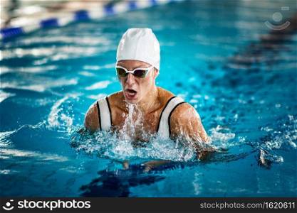 Female swimmer on training in the swimming pool. Breaststroke swimming style