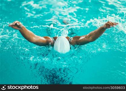 Female swimmer on training in the swimming pool. Butterfly swimming style