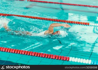 Female swimmer on training in the swimming pool. Front crawl swimming style
