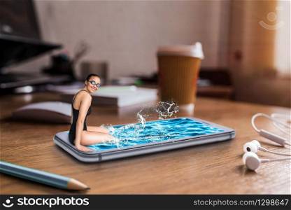 Female swimmer sits on the edge of large phone screen with water, table with big coffee cup on background. Mobile and communication technology addiction, social addicted people. Scaling effect