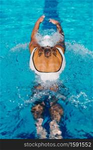 Female swimmer with tattoos swimming butterfly on training