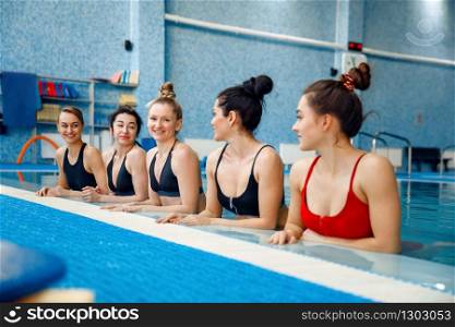 Female swimmers group poses at the poolside. Women fit training in the water, sport swimming, fitness workout in pool. Female swimmers group poses at the poolside