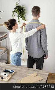 female tailor measuring male clients shirt