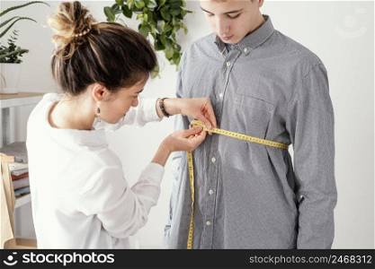 female tailor measuring male clients shirt 3