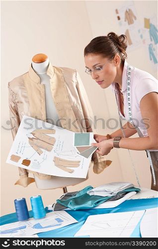 Female tailor working at fashion studio with mannequin
