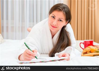 female takes notes in a notebook lying on the bed