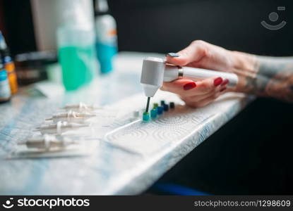 Female tattoo artist prepares color ink. Preparation for tattooing, tattoo salon. Female tattoo artist prepares color ink