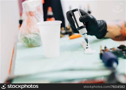 Female tattooist preparing the dyes she?s going to work with using black ink. Tattoo concept.. Female tattooist preparing the dyes she?s going to work with.