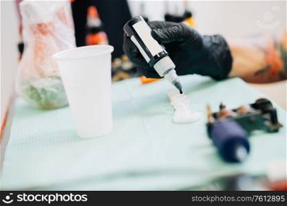 Female tattooist preparing the dyes she?s going to work with using black ink. Tattoo concept.. Female tattooist preparing the dyes she?s going to work with.