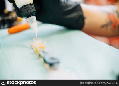 Female tattooist preparing the dyes she?s going to work with using white ink. Tattoo concept.. Female tattooist preparing the dyes she?s going to work with.