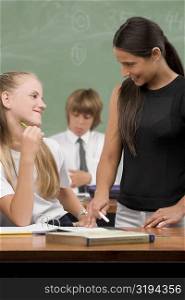 Female teacher and a schoolgirl smiling at each other in a classroom