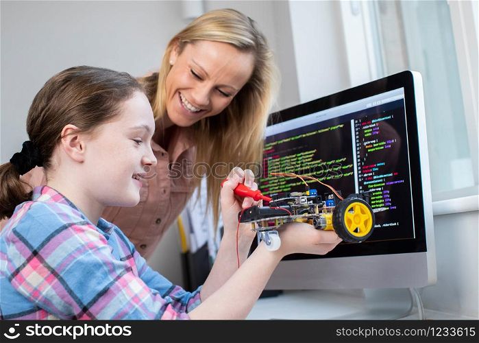 Female Teacher Helping Girl Building Robotic Car In Science Lesson