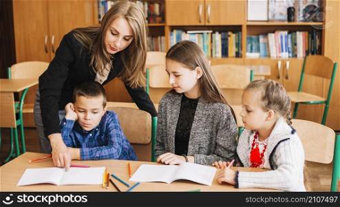 female teacher helping pupils studying process