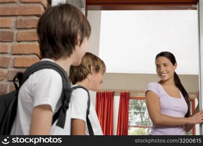Female teacher looking at two schoolboys and smiling