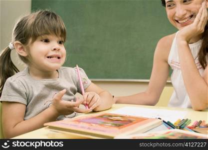 Female teacher smiling with her student sitting beside her